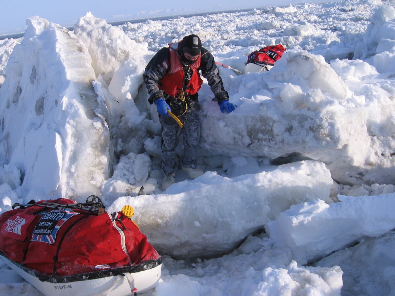 Karl Bushby in a survival suit among broken pack ice on the Bering Strait crossing, his sled beside him.
