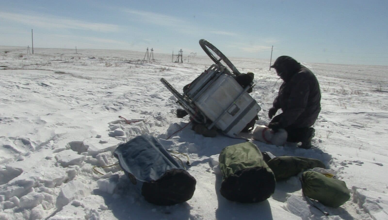 Karl Bushby kneeling beside his cart on the frozen, wind-scoured Mongolian steppe under a pale winter sky.