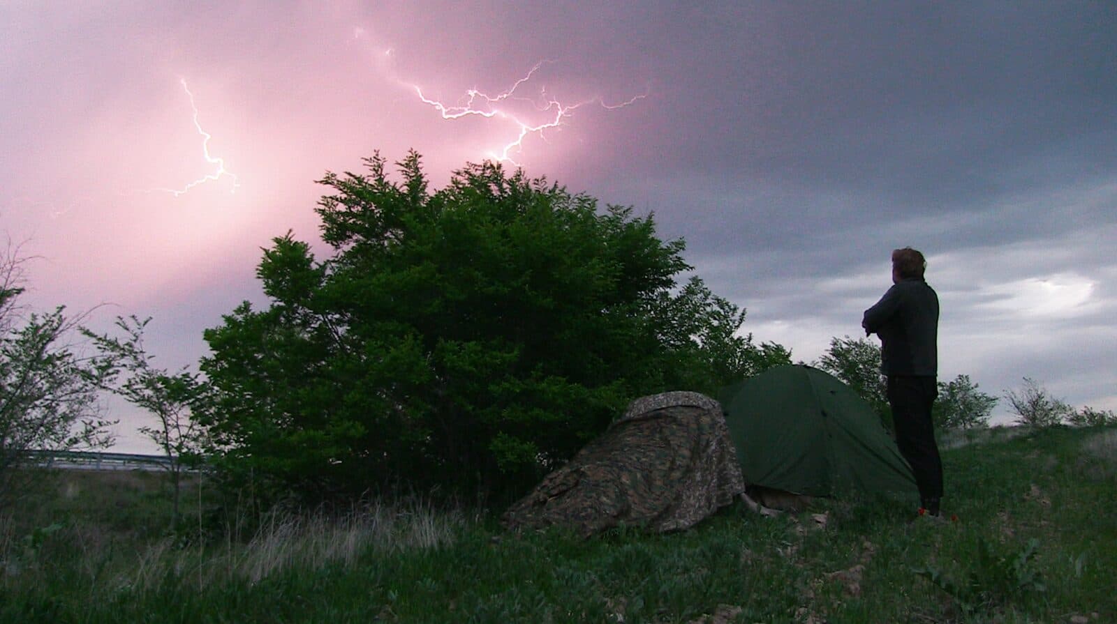 Karl Bushby beside his tent on the Kazakh steppe, watching forked lightning split a darkening pink sky.