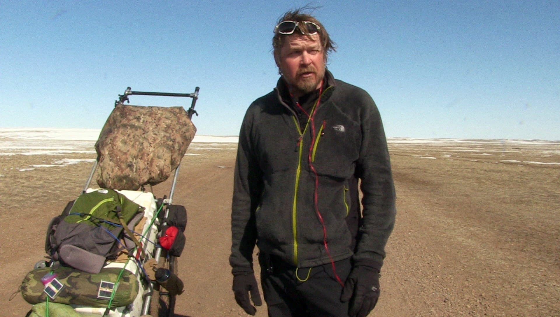 Karl Bushby beside his expedition cart in a cold, open landscape.